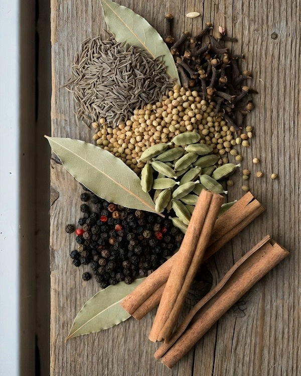 Whole spices used in garam masala including cinnamon, cloves, and cardamom