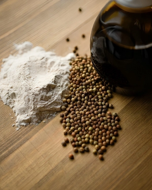 Ingredients for Borodinsky bread including whole-grain rye flour, coriander seeds, and a bottle of dark molasses.