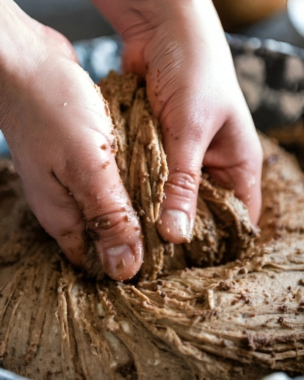 Baker kneading sticky, dense whole-grain rye dough for Borodinsky bread.