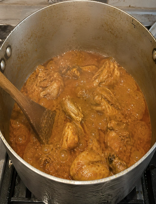 Chicken curry bubbling gently on low heat with thick gravy and oil separating at the top