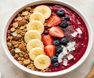thick berry smoothie bowl with banana slices, granola, strawberries, blueberries and chia seeds top view healthy 5-minute breakfast