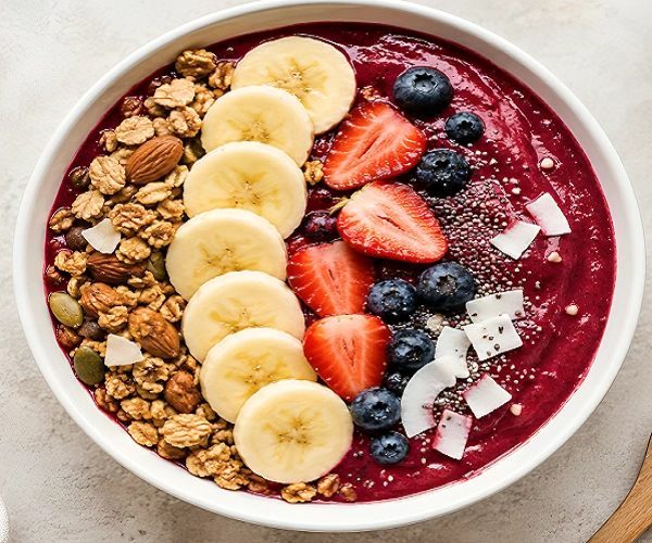 thick berry smoothie bowl with banana slices, granola, strawberries, blueberries and chia seeds top view healthy 5-minute breakfast