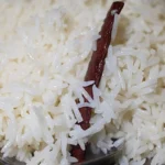 Fluffy cooked basmati rice with separated grains and a cinnamon stick served with a spoon