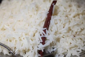 Fluffy cooked basmati rice with separated grains and a cinnamon stick served with a spoon