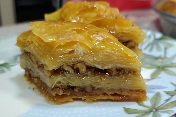 Albanian baklava with crispy phyllo pastry layers, walnut filling, and glossy lemon syrup served on a plate