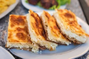 Traditional Albanian byrek sliced on plate showing crispy golden flaky layers
