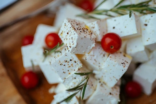 Fresh Albanian djathë i bardhë cheese cubes garnished with herbs and cherry tomatoes on rustic wooden board