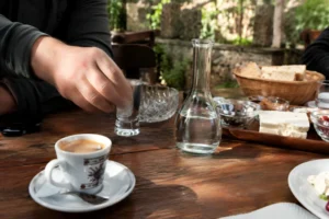 Traditional Albanian drinks table with raki, Turkish coffee, dhallë yogurt drink, bread and cheese served in a rustic outdoor setting