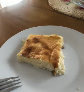 Homemade Albanian qumeshtor slice on a white plate with a golden top and soft custard texture