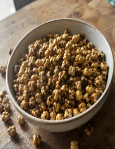 A close-up shot of a white ceramic bowl filled with traditional Turkish çifte kavrulmuş double-roasted leblebi chickpeas on a rustic wooden table.