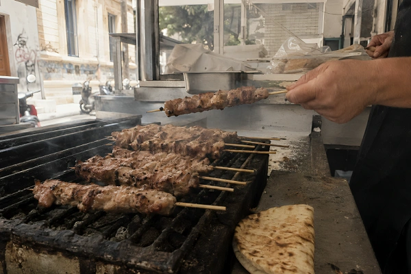 Pork souvlaki skewers grilling over hot charcoal at a local food stall.