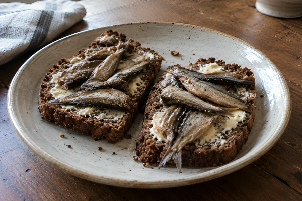 Two slices of dark Estonian rye bread topped with butter and pickled Baltic sprats