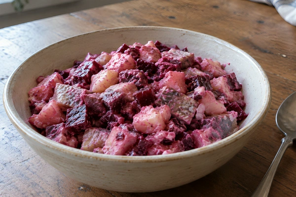 A vibrant pink Estonian Rosolje salad made with diced beetroot, potatoes, herring, and cream dressing