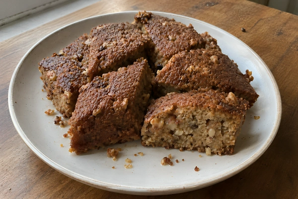 A white plate filled with diamond-cut slices of traditional Albanian Shendetlie honey walnut cake.