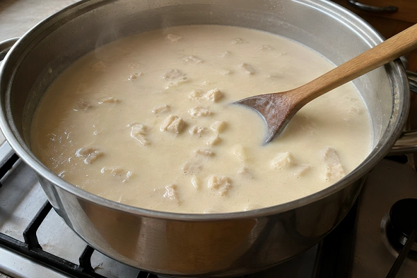 Creamy tripe soup with chopped tripe pieces simmering gently in a large pot.