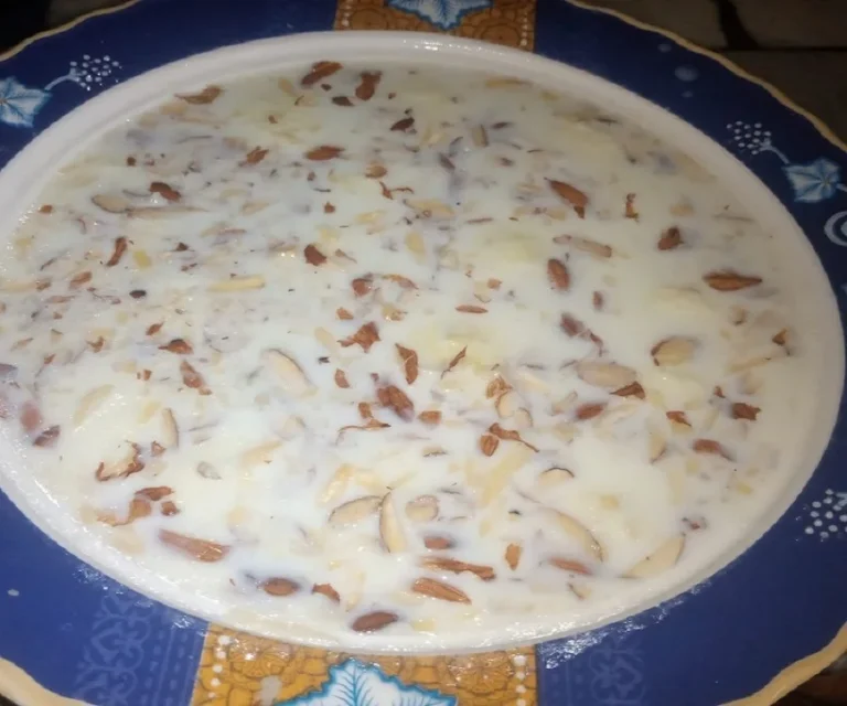 Homemade ras malai topped with sliced almonds and pistachios served in a blue patterned dish.