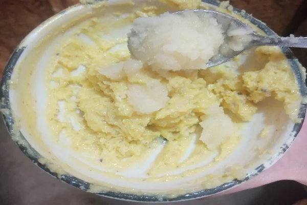 Mixing ras malai powder with ghee and beaten egg in a small bowl.